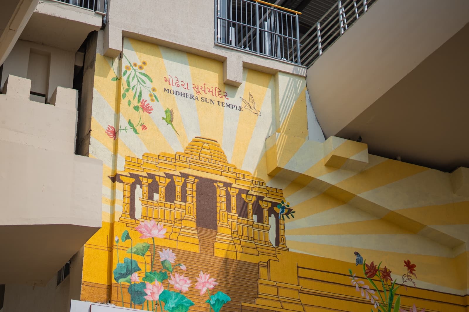 Mural depicting the Modhera Sun Temple with sunburst rays, lotus flowers and birds at a metro station