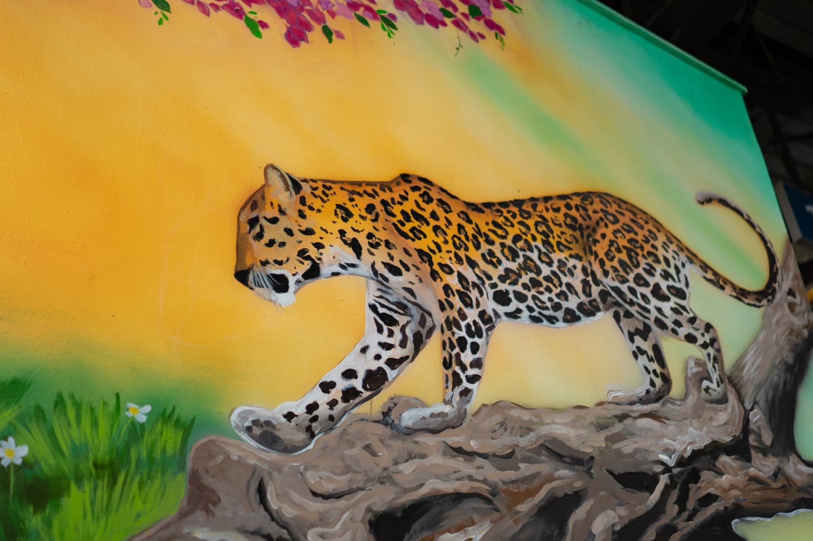 Close-up realistic mural of a leopard walking along a branch, painted on a metro station wall