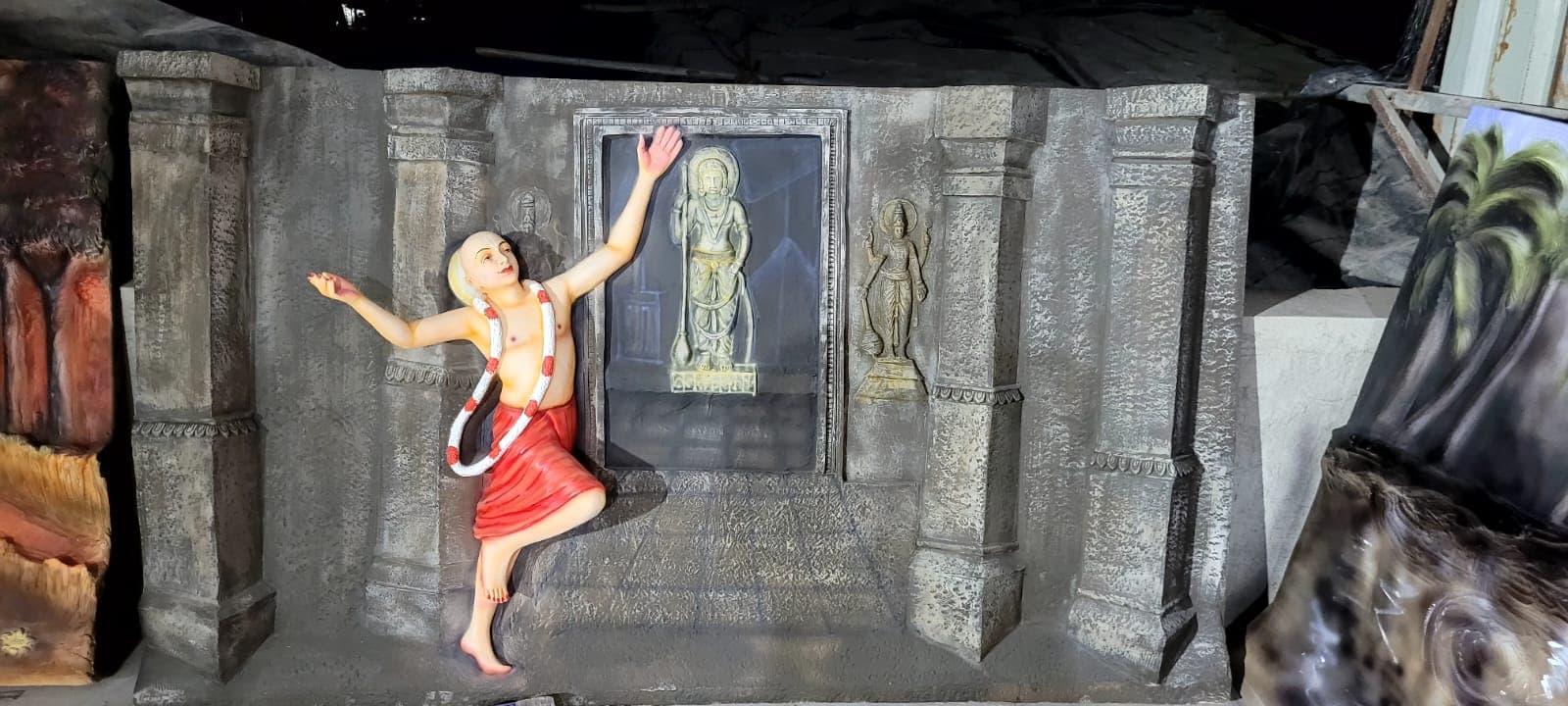 FRP relief panel of a devotee in an ecstatic dance pose beside a temple sanctum