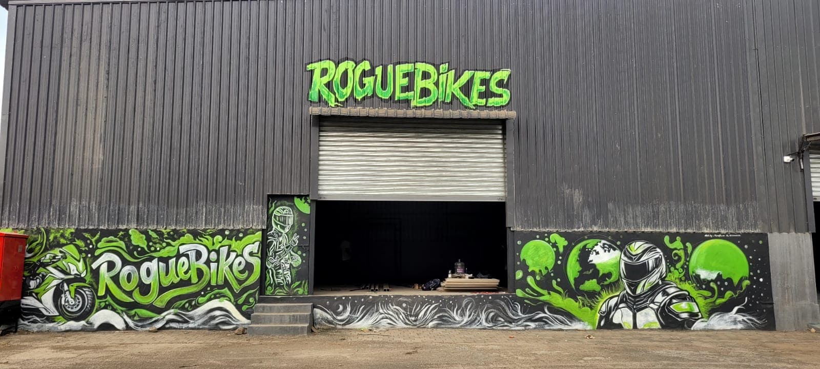 Green and white graffiti artwork across the RogueBikes sport bike showroom facade, with brand lettering, a rider on a motorcycle and a helmeted figure