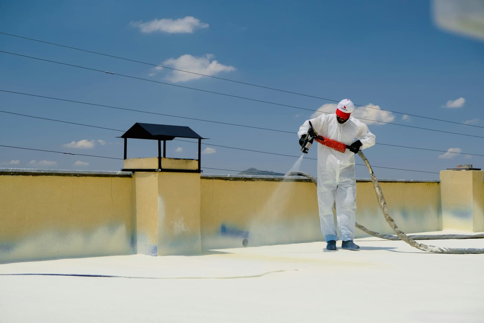Worker applying waterproofing coating on a building terrace